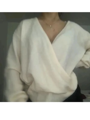 Omlott stickad vit tröja - Mysig stickad tröja i vit färg med omlott-design och v-ringning både fram och bak. Tröjan har långa ärmar och ribbade muddar vid ärmslut och nederkant. Perfekt för lager-på-lager och chill vibes. Öppningen kan man använda fram eller på ryggen❤️