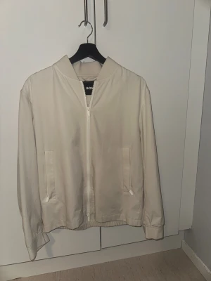 Vit vindjacka från BOSS - Helt ny jacka ifrån hugo boss. Kommer i en liten påse där man kan förvara jackan i. Väldigt snygg och stilren, kvitto medföljer.