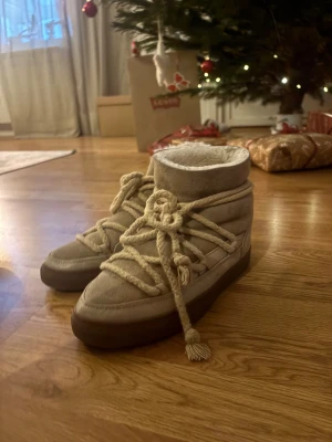 Beige Inuikii boots med snörning - Säljer ett par beige boots från Inuikii med grov snörning och platt sula. Skorna är fodrade med mjukt material och har en ovandel i mocka och skinn. Perfekta för kalla dagar och har en chunky vibe som sticker ut. Använda fåtal gånger. Låda ingår
