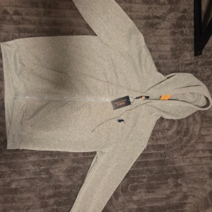 Ralph lauren - Helt ny Ralph Lauren zip-tröja i mycket fint skick. Tröjan är oanvänd och kommer i hög kvalitet med klassisk och stilren design. Perfekt för både vardag och finare tillfällen.