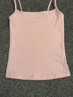 Ljusrosa linnetopp från Garage - Säljer en ljusrosa linnetopp från Garage i storlek XXS. Toppen har smala axelband och ärmlös design med enkel, rak form. Materialet är mjukt och stretchigt, perfekt för varma dagar. Stilren och basic utan mönster eller extra detaljer. Sitter tajt 