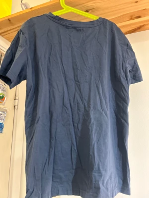 Blå t-shirt från 157 i bomull - En enkel blå t-shirt från 157 i storlek S, tillverkad i mjuk 100% bomull. Modellen har rund hals och korta ärmar, perfekt för en chill och avslappnad stil. Passar dig som gillar basic och bekväma plagg.