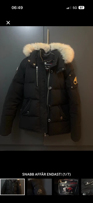 Svart Moose Knuckles pufferjacka med päls - Säljer en svart  vinterjacka  från Moose Knuckles med ikonisk logga på ärmen och fluffig vit päls runt huvan. Jackan har flera dragkedjor, knappar och praktiska fickor.  