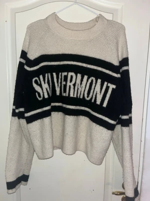  Stickad tröja  - Säljer en stickad tröja från H&M i storlek M med SKI VERMONT-tryck över bröstet. Tröjan är vit med svarta breda ränder och har en rund hals samt långa ärmar. Den är ribbad i muddar och hals, perfekt för dig som gillar retrovibbar och sportig stil eller bara vill ha en snygg tröja i fjällen.