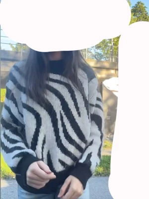 Zebramönstrad stickad tröja svart/vit - Säljer en riktigt snygg stickad tröja med zebramönster i svart och vitt. Tröjan har en loose passform, ribbade muddar och rund hals. Perfekt för dig som vill sticka ut lite extra i höst eller vinter!