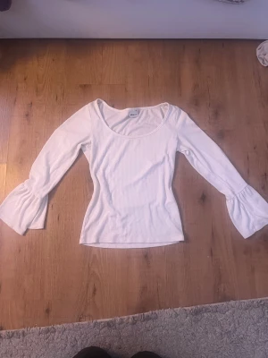 Vit ribbad topp med trumpetärm Gina Tricot - Supersnygg vit ribbad topp från Gina Tricot i storlek XS. Modellen har långa trumpetärmar och en rundad halsringning som ger en fräsch vibe. Materialet är mjukt och stretchigt, perfekt för dig som gillar slim fit och stilrena detaljer. Den är typ inte alls använd. Har använt den 1-2 gånger. Säljer då den inte kommit till användning.