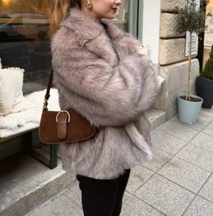 pälsjacka från design by si - Intressekoll på en supermjuk och fluffig beige pälsjacka från Design by si, med bred krage och långärmad design. Jackan har en loose passform och är perfekt för dig som vill ha en cool och lyxig vibe. Materialet är syntetpäls som känns riktigt skönt och värmande. Passar dig som gillar statement-plagg.