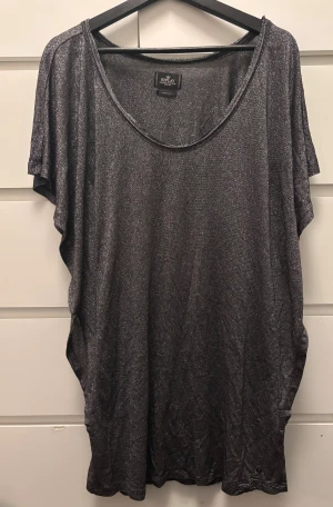 Glittrig silver topp/klänning från Replay XS - Säljer en glittrig silverfärgad topp/klänning från Replay i storlek XS. Toppen har loose passform, korta ärmar och rund halsringning. Materialet är syntet med metallictrådar som ger en skimrande effekt. Perfekt för dig som vill sticka ut med en cool och trendig look.