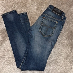 Blå jeans från tiger of Sweden slimfit  - Snygga blå jeans från tiger of Sweden med klassisk femficksdesign och slim passform. Jeansen har en mörk tvätt med lätt slitning och kontrastsömmar. Passar dig som gillar en enkel och stilren look. Materialet är robust denim med skön känsla.
