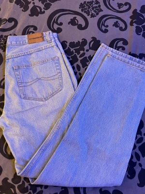 Ljusblå jeans från Zantos Jeanswear - Snygga ljusblå jeans från Zantos Jeanswear med klassisk femficksdesign, bruna sömmar och läderpatch bak. Modellen har rak passform och dragkedja i gylfen. Perfekta för dig som gillar en clean och tidlös look.