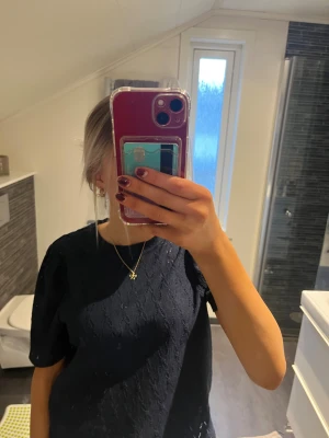 Mörkblå spetsblus med puffärm - Säljer en mörkblå blus med korta puffärmar och vacker spetsdetalj över hela toppen. Blusen har rund hals och ett elegant, feminint uttryck som passar dig som gillar stilrena detaljer. Perfekt att matcha med smycken för en extra touch.