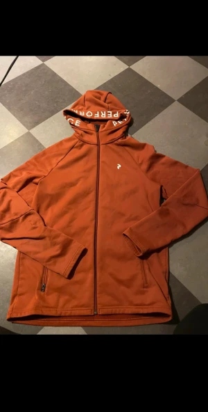 Orange hoodie från Peak Performance - Snygg Peak Performance zip hoodie som är väl använd (se bild) därav priset. Storlek S men passar även M