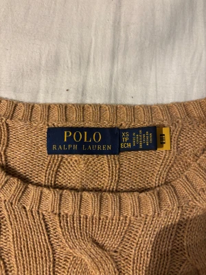Beige kabelstickad tröja Polo Ralph Lauren - Snygg beige kabelstickad tröja från Polo Ralph Lauren i storlek XS(ganska stor i storleken så den passar även S). Tröjan har en rund hals. 