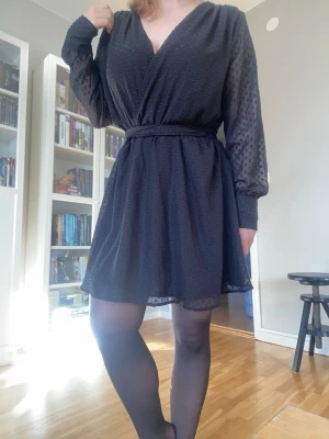 Svart klänning - Svart midiklänning från Bik Bok med ”prickar” (?) Ärmarna är mer transparanta, nästan mesh-liknande i material. Strl: L. Har ett långt, avtagbart band i två öglor längs midjan som går att justera passformen med. Använd 2 gånger ute, som ny. Läs gärna bion innan köp.