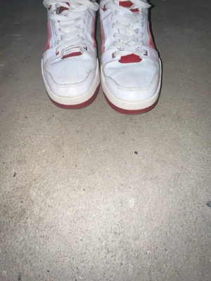 Puma Slipstream sneakers vit/röd - Säljer ett par Puma Slipstream sneakers i storlek 43. Skorna är vita med röda detaljer och guldlogga på plösen. De har snörning, rund tå och platt sula. Ovandelen är i skinn och textil, med perforeringar för ventilation. Snygg retrostil med kontrastfärger och klassisk Puma-design.