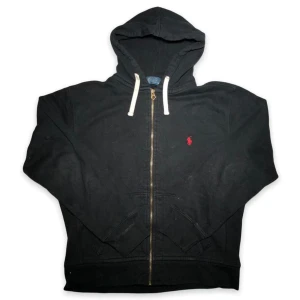 Ralph Lauren zip svart med röd logga  - Tja säljer en Ralph lauren zip i storlek M den är svart och har röd logga. Den har inga tecken på användning och har bra och normal passform 