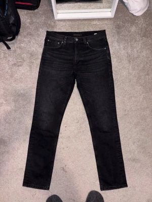 Nudie Jeans Lean Dean 30/30 - Säljer ett par feta svarta Nudie Jeans Lean Dean i storlek 30/30. Modellen har en relativt slim passform. Perfekta för dig som gillar stilrena svarta jeans. Hör av dig vid frågor och funderingar!