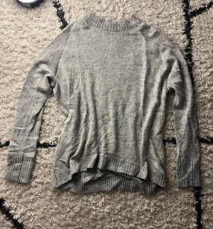 Grå stickad tröja från Weekday - Mjuk och enkel grå stickad tröja med ribbad hals, ärmslut och nederkant. Tröjan har långärmad design och en något lös passform