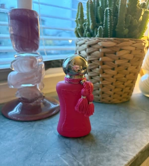 Oriana - Snygg och trendig parfym från Parfums de Marly i en rosa flaska med dekorativa tofsar. Perfekt för dig som vill sticka ut och addera en färgklick till din samling. 30ml och endast testad. 