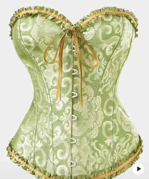 Grön korsett med gul snörning - Säljer en grön korsett med vackert mönster i ljusgrönt och beige. Korsetten har gul snörning fram och bak, samt dekorativa volanger och satinband längs kanterna. Formad för att framhäva midjan och har metallknappar framtill. Perfekt för dig som vill sticka ut!