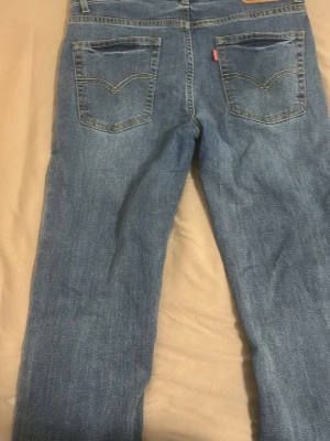 Levi's 510 Skinny jeans blå - Säljer ett par Levi's 510 Skinny jeans i klassisk blå tvätt med gul kontrastsöm. Modellen har fem fickor, bälteshällor och knappgylf. Jeansen är tillverkade i slitstarkt bomullsmaterial och har en smal passform som sitter tajt längs benen.