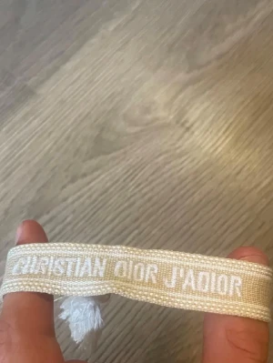 Dior armband - Säljer en beige dior armband med justerbara tofsar 