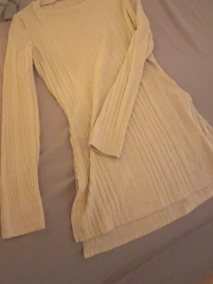 Beige ribbad långärmad tröja - Säljer en beige långärmad tröja med ribbad struktur. Tröjan har en enkel rund hals och är lite längre i modellen, vilket ger en chill och snygg look. Perfekt att matcha med jeans eller leggings för en avslappnad stil. Storlek Xs