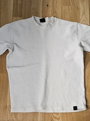 Vit ribbad långärmad tröja Pull&Bear - Säljer en stilren vit långärmad tröja från Pull&Bear i storlek S. Tröjan har ett ribbat tyg som ger en schysst struktur och en enkel rund halsringning. Perfekt för dig som gillar cleana och minimalistiska plagg med lite extra känsla i materialet.