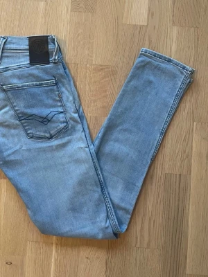 Replay Anbass ljusblå jeans - Säljer ett par Replay Anbass Hyperflex jeans i ljusblå tvätt. Klassisk femficksmodell med raka ben och normal passform. Jeansen har snygga kontrastsömmar och Replay-logga på fickan. Perfekta för dig som gillar stretchiga och bekväma jeans.
