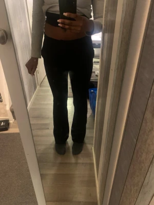 Svarta kostymbyxor  - Säljer ett par svarta bootcut byxor med hög midja. Byxorna har en snygg, figurnära passform upptill och blir vidare nedtill vid benen. Materialet känns mjukt och stretchigt, perfekt för dig som gillar bekväma och stilrena plagg.