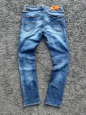 Jacob Cohen J696 (Nick) - Jacob Cohën J696 Comfort i blå tvätt med snygg fade. Handgjorda i Italien med lyxig känsla, ikoniska detaljer.    📏 Mått: Innerben 77 cm, midja 42 cm, ytterben 104 cm  📐 Passform: Slim fit – strl 33, passar även 32 (98% bomull / 2% elastan)  ✅ Skick: 9/10 - toppskick. Lite strån avfallna på läderpatchen. Denimet och allt annat är helt i toppskick utan defekter!  🎅 Modell: Personen på bilden är 187 cm 🧵 Modell: J696 Comfort 🧩 Material: Premium Denim fr 🇯🇵  ‼️Skickas samma dag eller dagen efter‼️