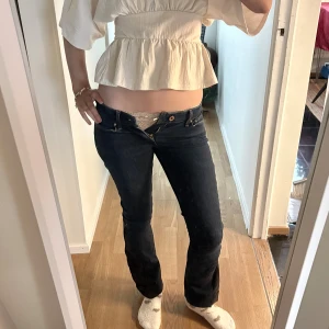 Bootcut jeans  - Säljer ett par mörkblå bootcut jeans från Levi's med låg midja. Byxorna har en unik svart panel längs utsidan av benen som ger en cool kontrast. Klassisk femficksmodell med knapp och dragkedja framtill. Perfekt för dig som gillar en lite retro vibe. passar xxs/xs