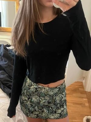 Svart croppad långärmad topp - Säljer en svart croppad topp med långa ärmar och rund hals. Enkel och stilren design som är lätt att matcha med olika outfits. Materialet känns mjukt och stretchigt, perfekt för dig som gillar bekväma och snygga plagg.