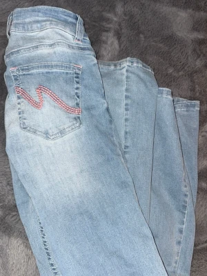 Lågmidjade jeans med rosa på fickorna - Säljer dessa lågmidjade jeans med rosa detalj på bakfickorna, köpta på nelly❣️säljer då de tyvärr inte kommit till användning, de är som nya🫶🏼 nypris 699