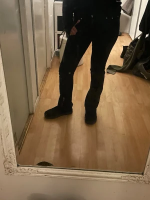 Svarta bootcut jeans från Gina Tricot - Säljer ett par svarta jeans från Gina Tricot med klassisk femficksdesign och silverfärgade nitar. Modellen har bootcut-snitt och normal passform, vilket ger en snygg siluett. Jeansen är tillverkade i bomull med lite stretch för extra komfort.