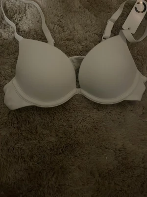 Vit push up-bh från Cubus A65 - Säljer en vit push up-bh från Cubus i modellen U Plush Deep Plunge Push Up. Bh:n har släta kupor, justerbara axelband och klassisk hakknäppning bak. Perfekt för dig som vill ha extra lyft och djup urringning.