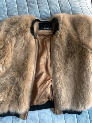 Beige pälsjacka från Rodebjer - Rodebjer fuskpäls jacka i nyskick. Känns som äkta päls. Storlek S men liten i passform så skulle säga att den är mer som XS