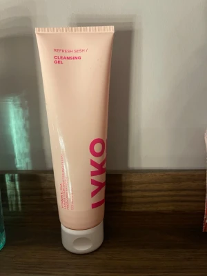 LYKO Refresh Sesh Cleansing Gel - En ljusrosa tub med LYKO Refresh Sesh Cleansing Gel, perfekt för att rengöra ansiktet. Tuben har rosa text och vitt lock, innehåller vitamin E och PHA för en fräsch och ren känsla. Smidig att använda och passar bra i badrumshyllan. Testat en gång!!! 150 ml