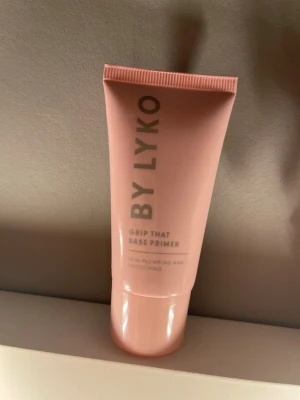 BY LYKO Grip That Base Primer - Grip That Base Primer från BY LYKO i en ljusrosa tub. Den är utformad för att ge en slät och plumpad hudkänsla, perfekt som bas innan smink. Tuben är gjord av plast och har en modern, stilren design med grå text.  Endast testad en gång! Orginal pris 130