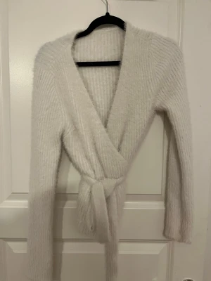 Vit omlottkofta med bälte - Mysig vit omlottkofta med bälte i midjan och långa ärmar. vet ej vart den är ifrån.