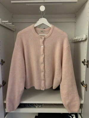 Ljusrosa kofta  - Mysig ljusrosa kofta från Gina tricot med rund hals och knappar framtill. Koftan har långa ärmar med ribbade muddar, perfekt för lager på lager under kyliga dagar.