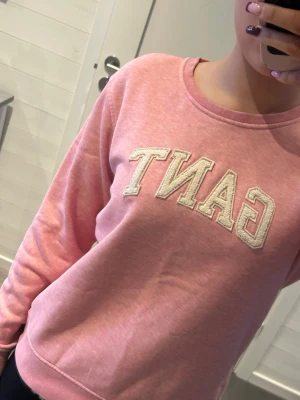 Rosa sweatshirt från GANT - Säljer en rosa sweatshirt från GANT med broderad logga i vitt framtill. Tröjan har rund halsringning och långa ärmar. Perfekt för dig som gillar en enkel men snygg stil. Materialet är mjukt och skönt, troligtvis bomullsmix.