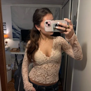 Rosa spetsblus från Gina Tricot - Supersnygg rosa spetsblus från Gina Tricot med blommigt mönster och v-ringning. Blusen är figurnära, har långa ärmar och är genombruten med fina spetsdetaljer. Perfekt att styla med jeans eller kjol för en trendig look. Aldrig använd, nytt skick!