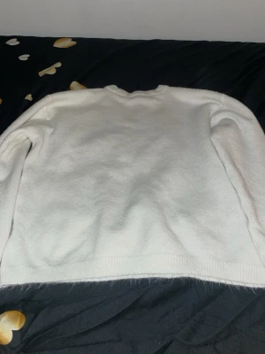 Vit stickad tröja med rund hals - Säljer en enkel och stilren vit stickad tröja med rund hals. Tröjan har långa ärmar och ribbade muddar vid nederkant och ärmslut. Perfekt att matcha med jeans eller kjol för en clean look.