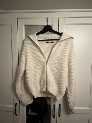 Vit stickad kofta från Bikbok - Säljer en vit stickad kofta från Bikbok i storlek XS. Koftan har ribbad struktur, lång ärm och dragkedja framtill. Hög krage som kan vikas ner för en chill look. Perfekt för lager-på-lager under hösten och vintern. Lite nopprig så som stickade tröjor oftast blir men fortfarande fint skick!