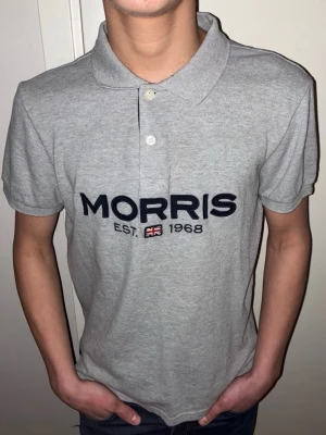 Grå pikétröja från Morris - Säljer en klassisk grå pikétröja från Morris med mörkblå broderad logga. Skicket är riktigt bra. Riktigt stilig och fin. Storlek M. Hör av er för  frågor. Mvh