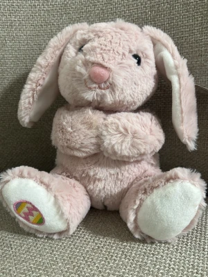 Rosa mjuk kanin gosedjur - Supersöt rosa kanin som gosedjur med långa öron och broderad nos. Kaninen har vita detaljer på tassar och öron, samt ett färgglatt äggmönster under ena tassen. Perfekt att ha som dekoration eller mysig kompis.