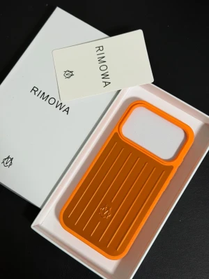 Orange iPhone 17 Pro mobilskal från Rimowa - Snyggt orange mobilskal från Rimowa med räfflad design och logga på baksidan. Skalets material är tålig plast och det har en modern look som sticker ut. Passar perfekt för dig som vill ha ett unikt och trendigt skydd till din mobil.