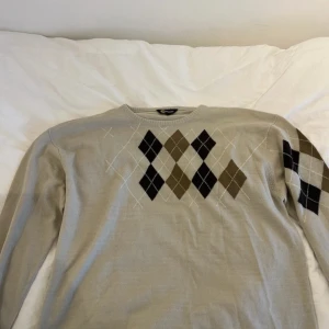 Beige argyle stickad tröja - Bra skick⭐️ storlek L, mått: längd: 66 cm, axelbredd: 58 cm, ärmlängd: 57 cm