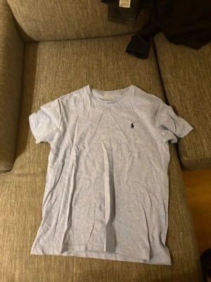 Ljusblå t-shirt från Ralph Lauren - Snygg ljusblå t-shirt från Ralph Lauren med klassisk rund hals och korta ärmar. T-shirten har den ikoniska lilla mörkblå Polo-loggan broderad på bröstet. Tillverkad i mjukt bomullsmaterial som känns skönt mot huden.